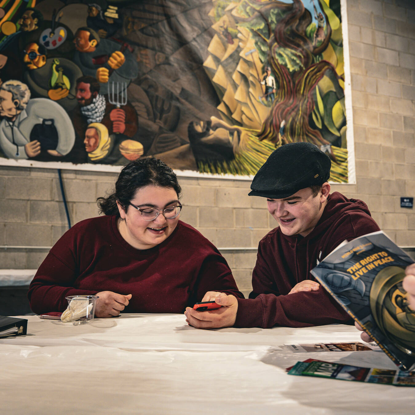Two students smiling while looking at a photo on one of the students' phones.